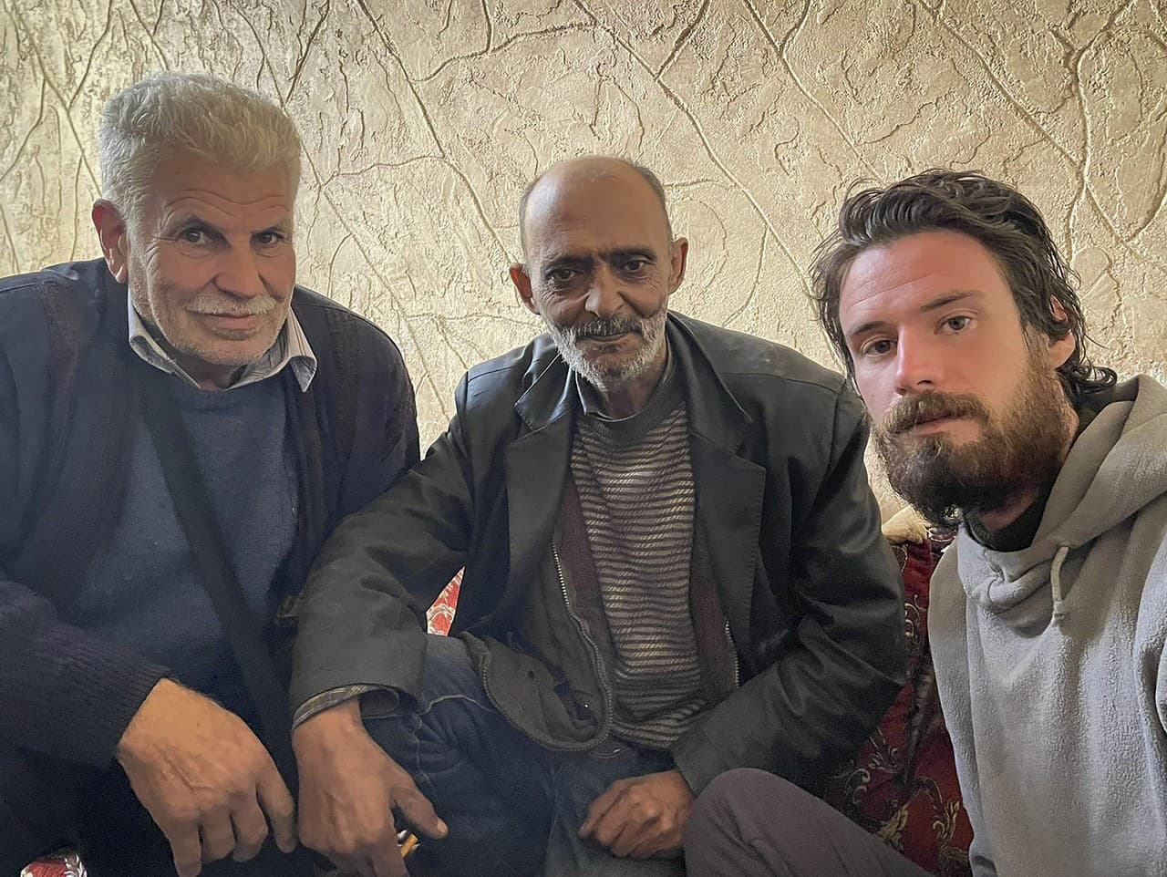 Americký občan Travis Timmerman (vpravo) sedí s Mosaedom al-Rifaiom (uprostred), ktorý ho našiel v sýrskej púšti a majiteľom domu (vľavo), kde našiel prístrešie v sýrskom Damasku 12. decembra 2024.