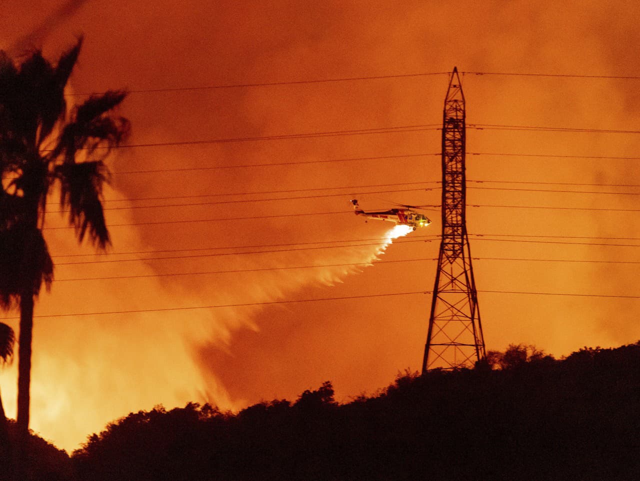 Vrtuľník zhadzuje vodu počas lesného požiaru v štvrti Mandeville Canyon.