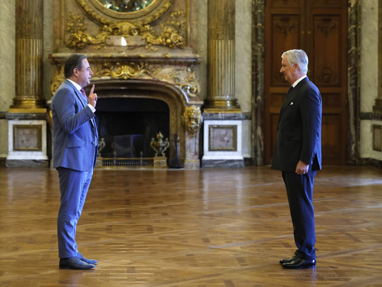 Nový belgický premiér Baart De Wewer (vľavo) zdvíha ruku pred belgickým kráľom Filipom počas prísahy novej belgickej vlády v Bruseli.