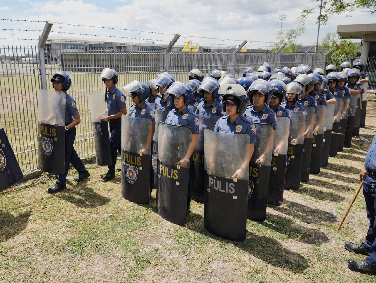 Bezpečnostní pracovníci stoja pred leteckou základňou Villamor po zatknutí bývalého prezidenta Rodriga Duterteho, utorok 11. marca 2025, neďaleko Manily na Filipínach.