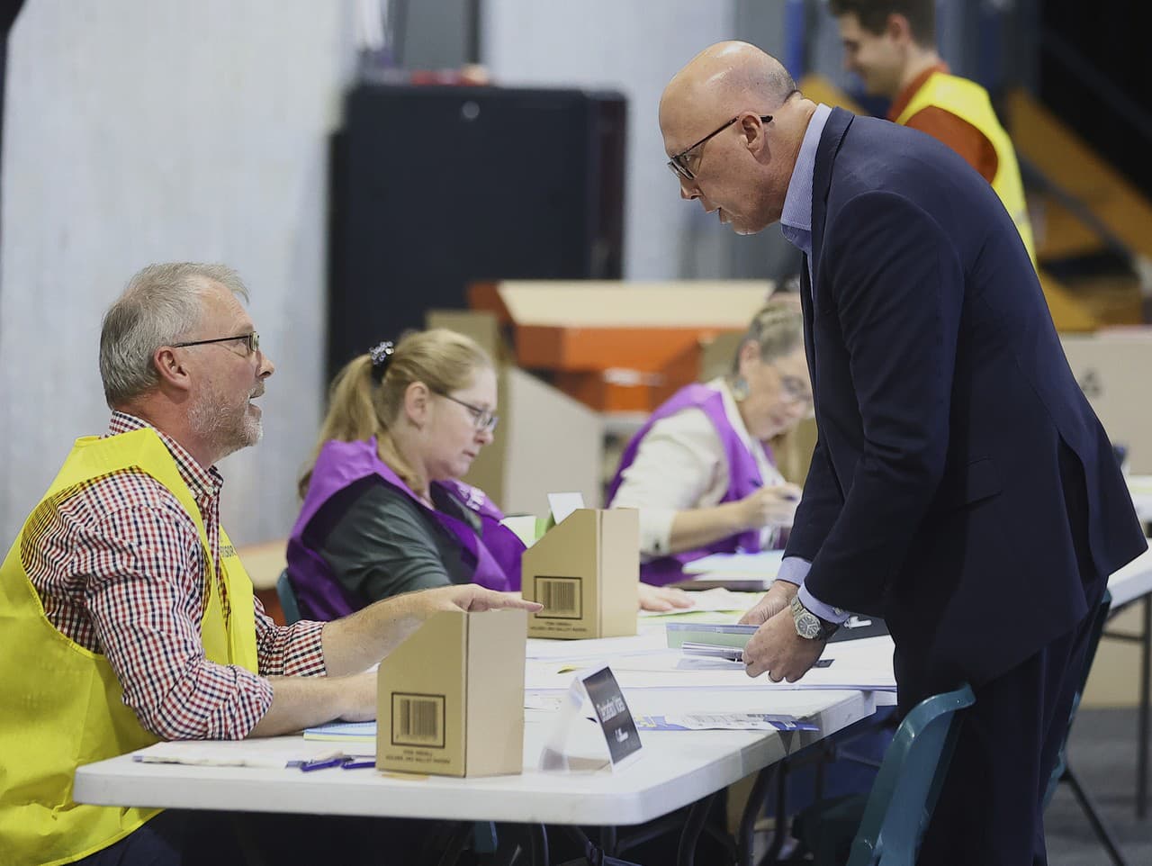 Predseda Austrálskej liberálnej strany Peter Dutton (vpravo) sa rozpráva s volebným úradníkom počas príprav na hlasovanie vo svojom volebnom obvode v Brisbane.