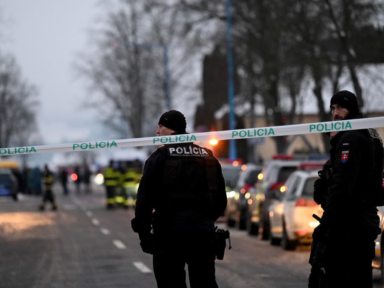 Policajti za policajnou páskou na ceste vedúcej ku Gymnáziu v Spišskej Starej Vsi v okrese Kežmarok, kde zahynuli po útoku žiaka nožom dve ženy a tretia žena utrpela stredne ťažké poranenia.