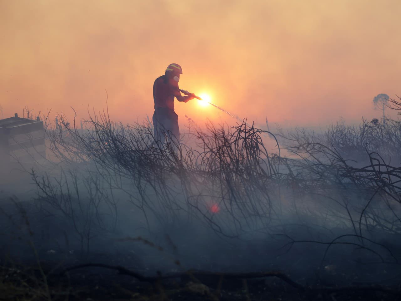 Hasič zasahuje počas lesného požiaru v štvrti Kyroneri na severozápade Atén