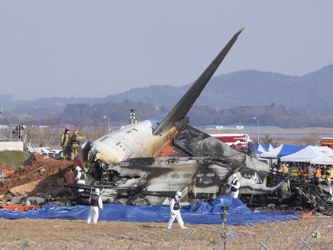 Hasiči a členovia záchranného tímu pracujú v blízkosti vraku osobného lietadla na medzinárodnom letisku Muan.