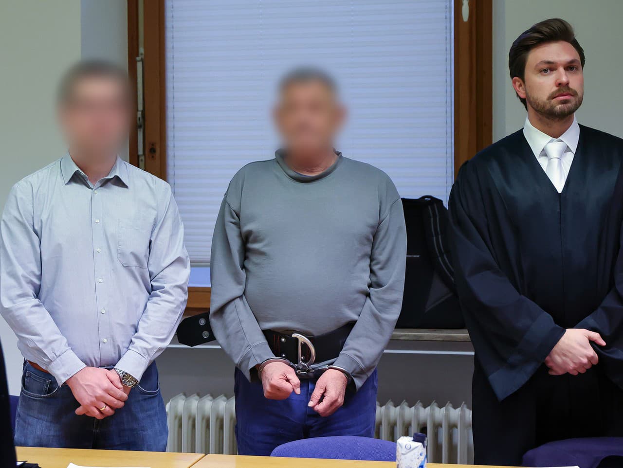 Sedemdesiatjedenročný bývalý americký vojak (uprostred) a jeho obhajca Johannes Makepeace (vpravo) stoja v súdnej sieni krajského súdu v nemeckom Schweinfurte