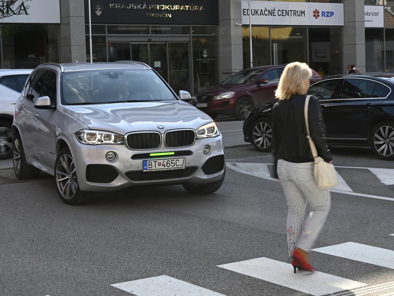 Chodkyňa prechádza cez priechod pre chodcov, pred ktorým zastavilo vozidlo s predným brzdovým svetlom umiestneným nad evidenčným číslom