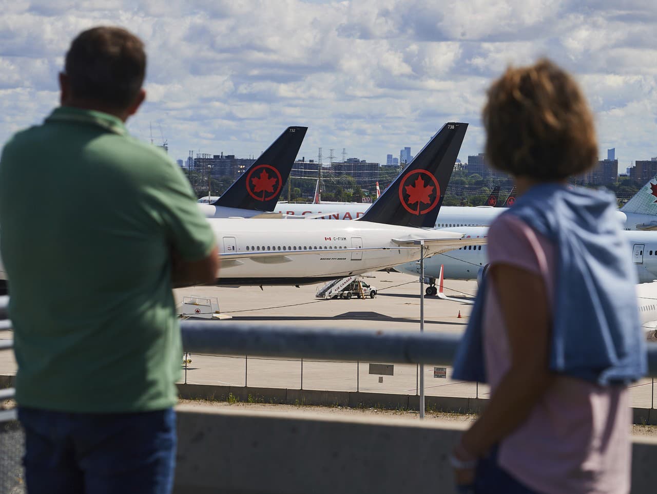 Cestujúci sa pozerajú na lietadlá spoločnosti Air Canada počas štrajku zamestnancov na letisku v Toronte