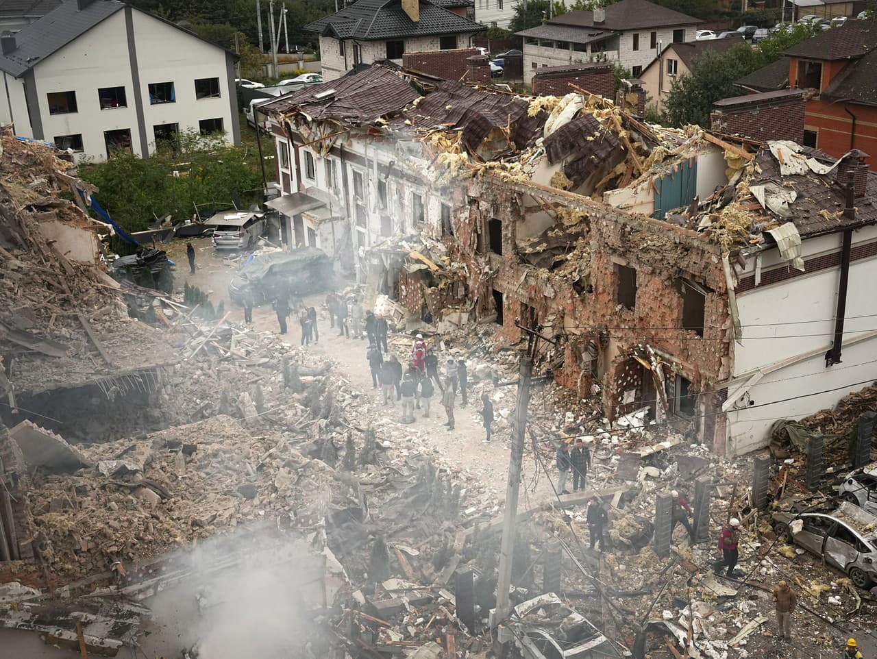Ľudia na mieste bytového domu zničeného počas ruského útoku v Kyjeve na Ukrajine