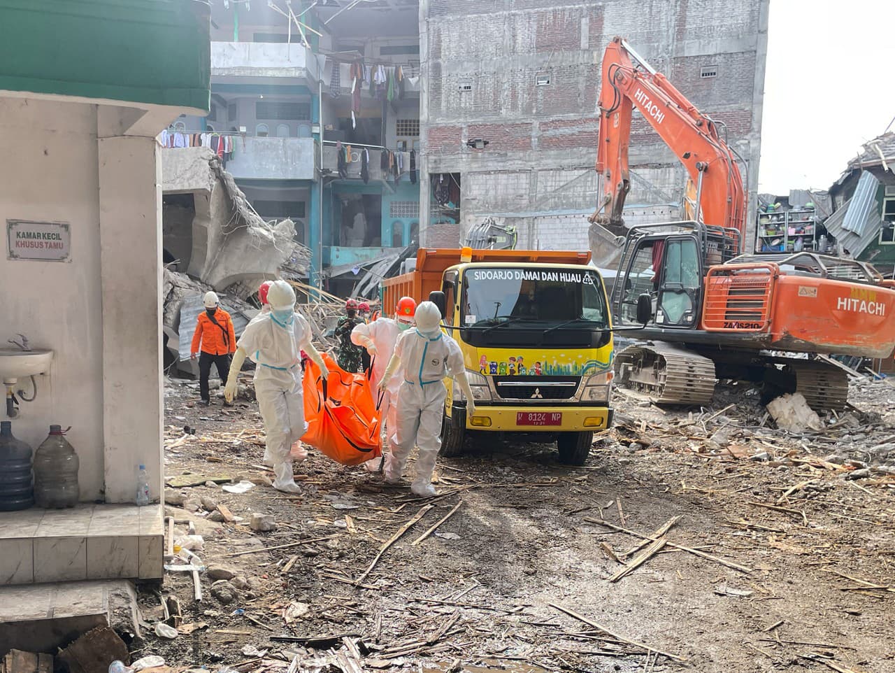 záchranári nesú telo novo nájdenej obete zrútenej budovy islamskej internátnej školy v meste Sidoarjo