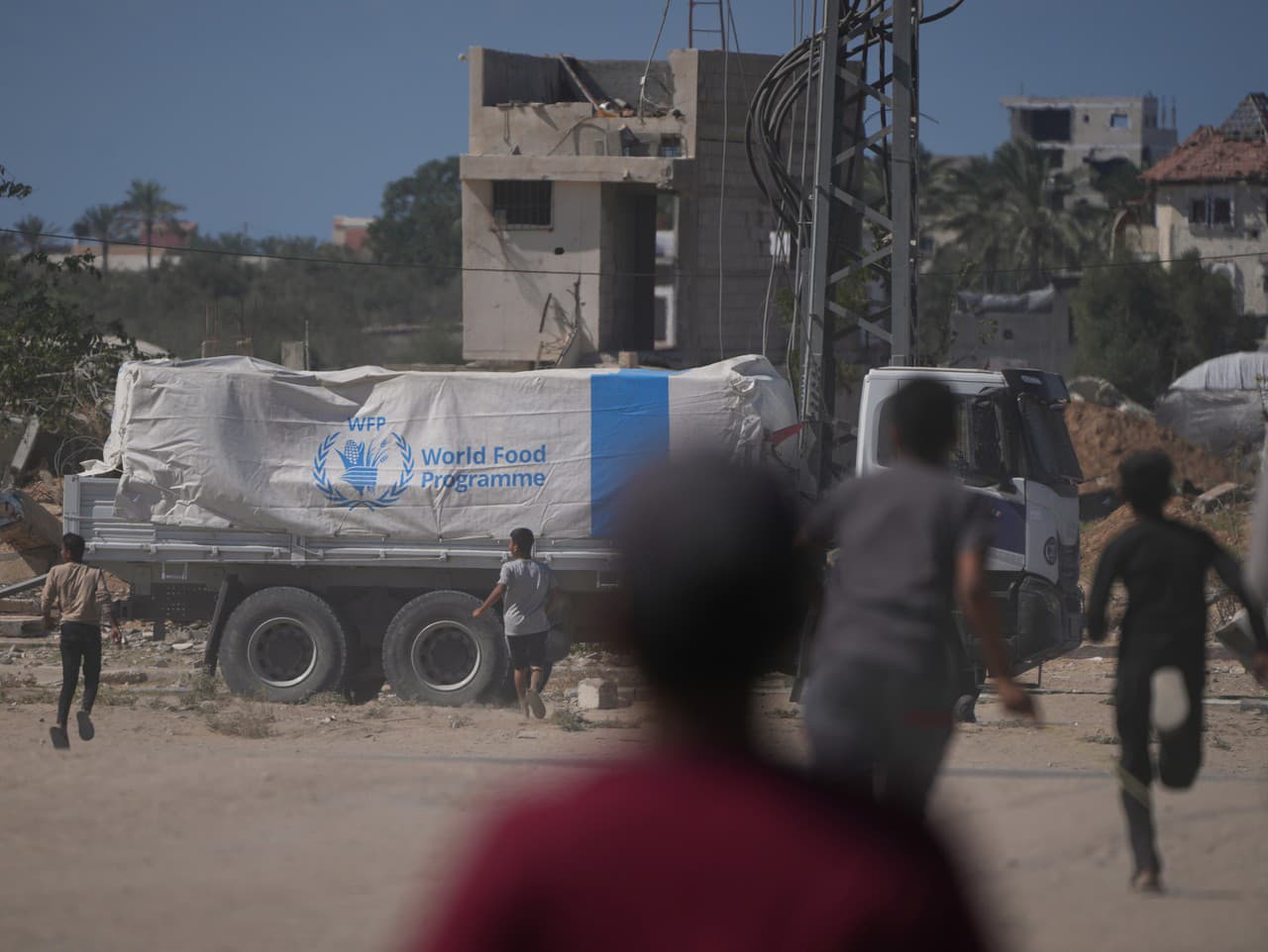 Vysídlení Palestínčania utekajú k nákladným autám s humanitárnou pomocou Svetového potravinového programu World Food Programme (WFP) v meste Dajr al-Balah, v centrálnej Gaze.