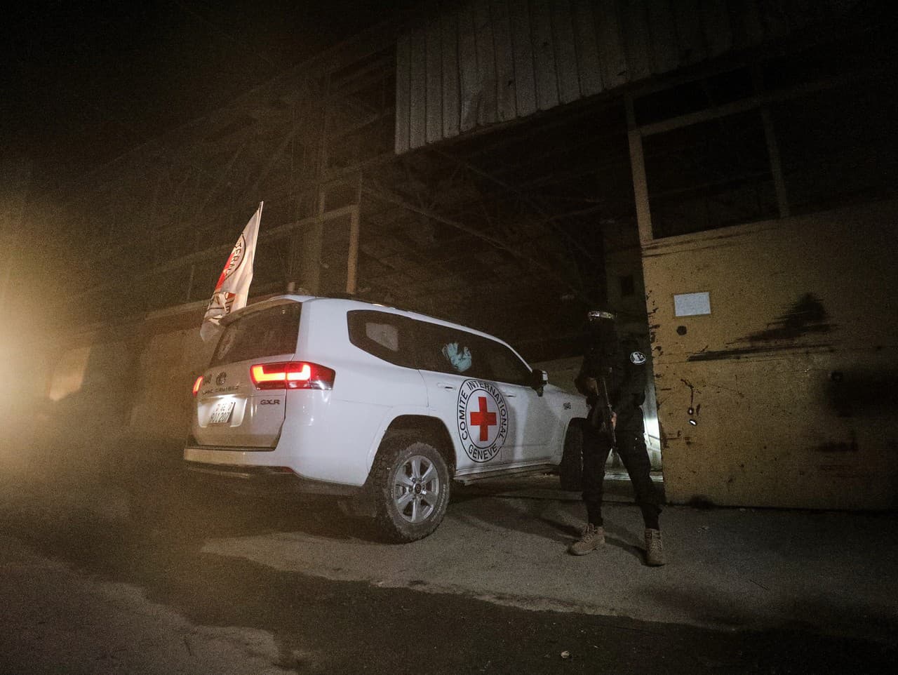 Ozbrojený militant z Brigády Izzadín al-Kassám, vojenskej odnože Hamasu, stráži vozidlá Červeného kríža, ktoré vchádzajú do skladu v meste Gaza, kde majú údajne vyzdvihnúť rakvy s telami štyroch mŕtvych rukojemníkov.