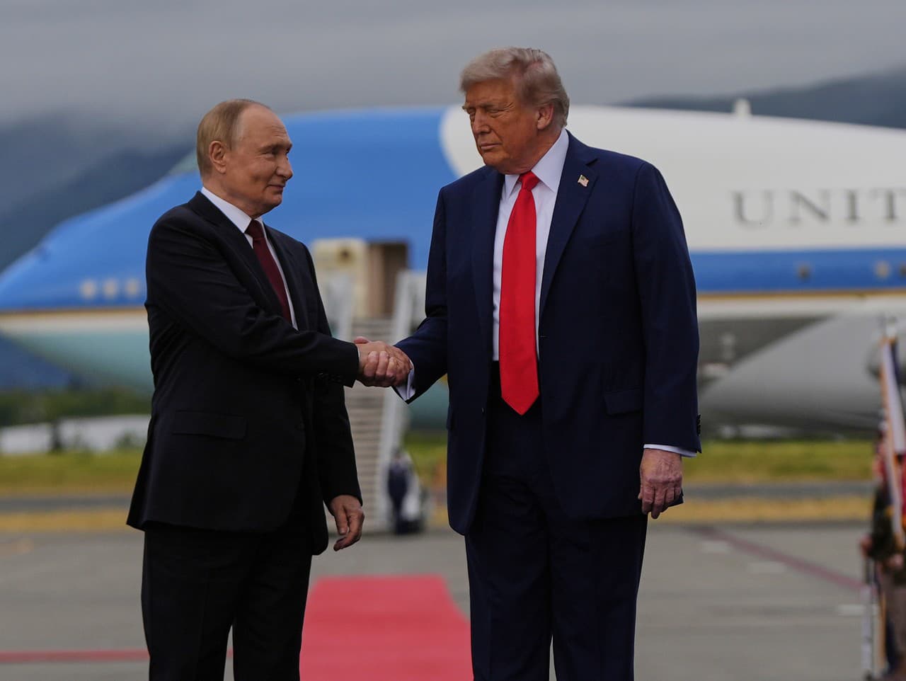 Donald Trump a Vladimir Putin si podávajú ruky na červenom koberci pred začiatkom summitu na Aljaške 