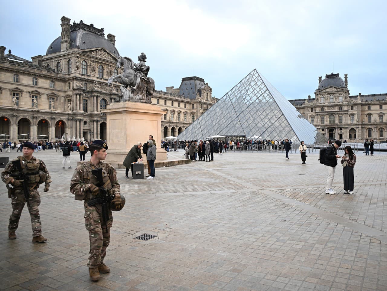 Vojaci hliadkujú, zatiaľ čo ľudia stoja v rade, aby sa pokúsili vstúpiť do múzea Louvre, hoci po nedeľňajšej lúpeži šperkov zostáva múzeum zatvorené celý deň.