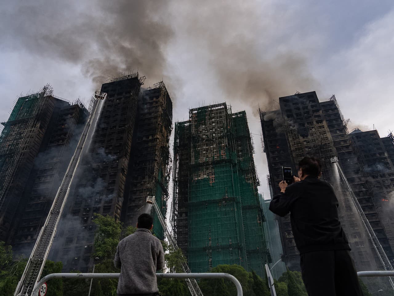 Hasiči pracujú na uhasení požiaru, ktorý vypukol v obytnom komplexe vo štvrti Tai Po v Hongkongu.