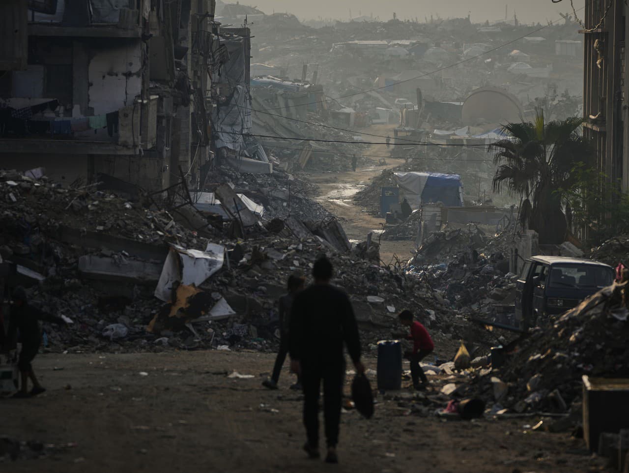 Palestínčania prechádzajú cez skazu, ktorú zanechala izraelská letecká a pozemná ofenzíva v meste Gaza.