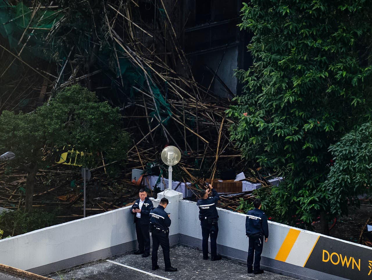 Policajti fotografujú miesto smrteľného požiaru, ktorý vypukol v rezidenčnom komplexe v štvrti Tai Po v Hongkongu.