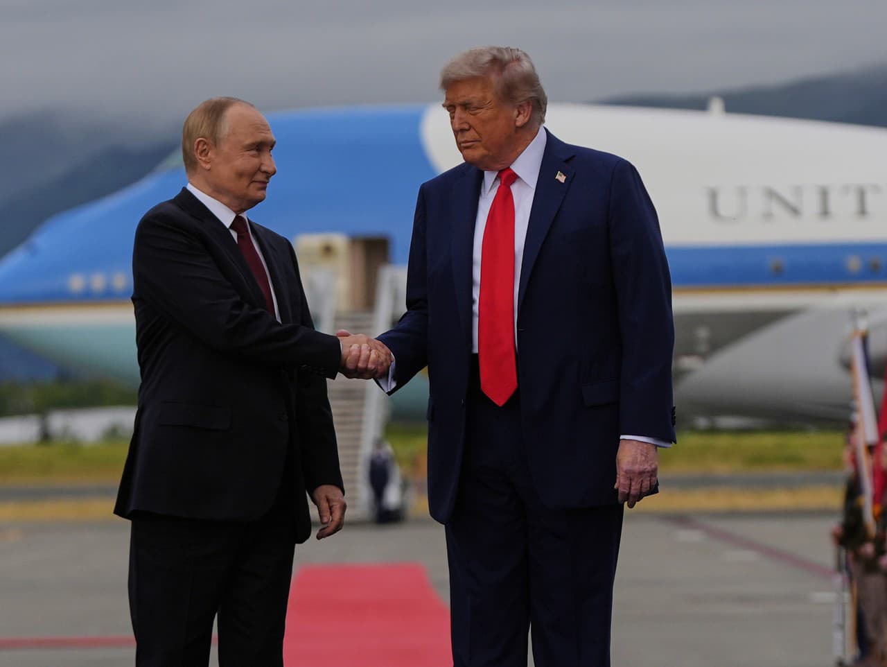 Donald Trump a Vladimir Putin si podávajú ruky na červenom koberci pred začiatkom summitu na Aljaške 