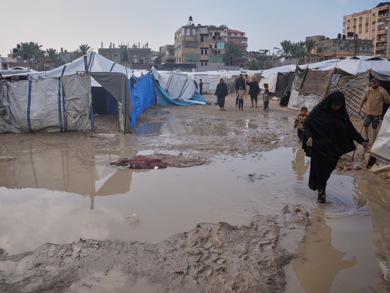 Palestínčania prechádzajú zaplavenou oblasťou v dočasnom stanovom tábore po silných dažďoch v Deir al-Balah v centrálnom pásme Gazy.
