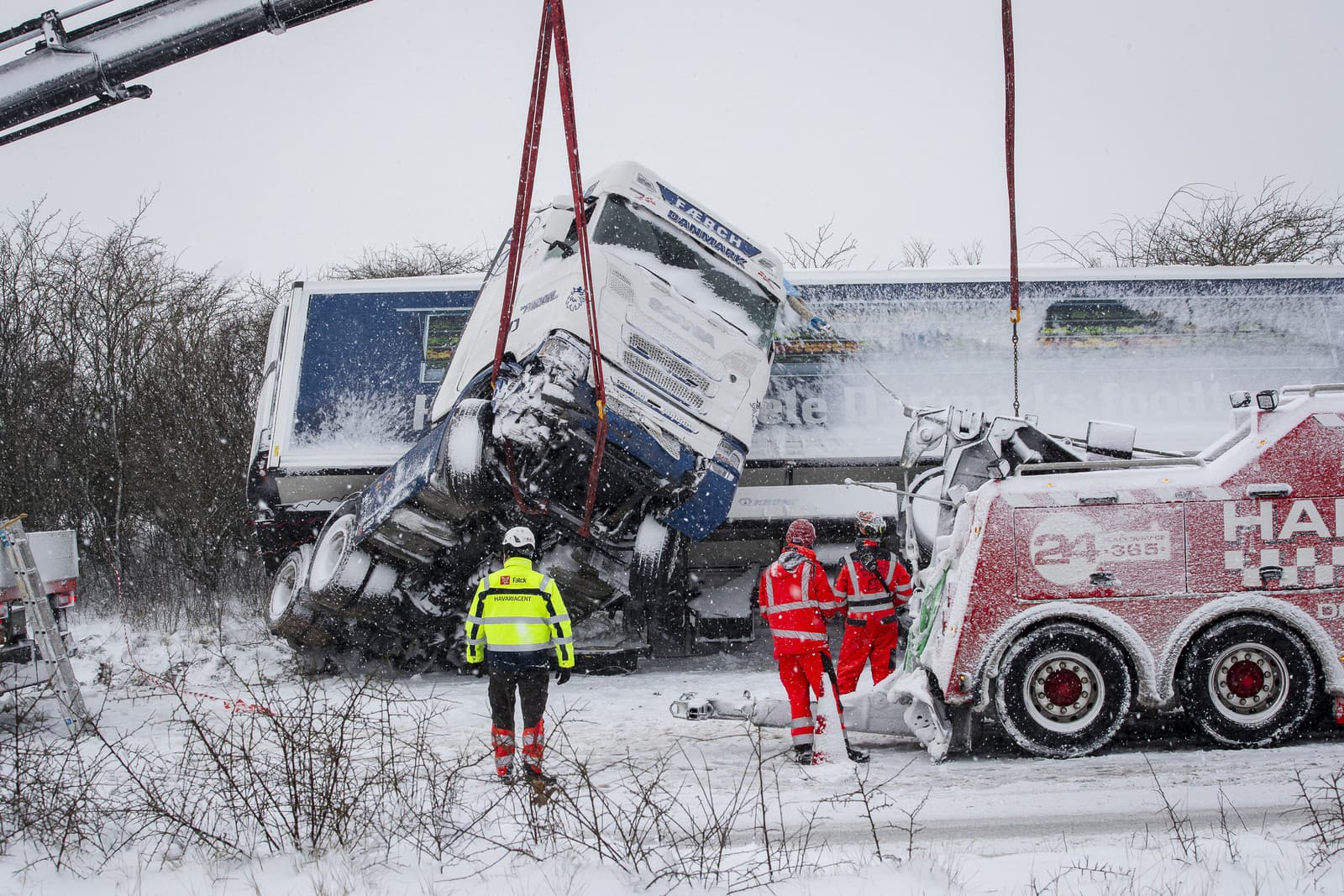 Záchranári sa snažia vyslobodiť nákladné auto, ktoré zišlo z cesty počas hustého sneženia vo Viborgu v strednom Jutsku v Dánsku v stredu 3. januára 2024.