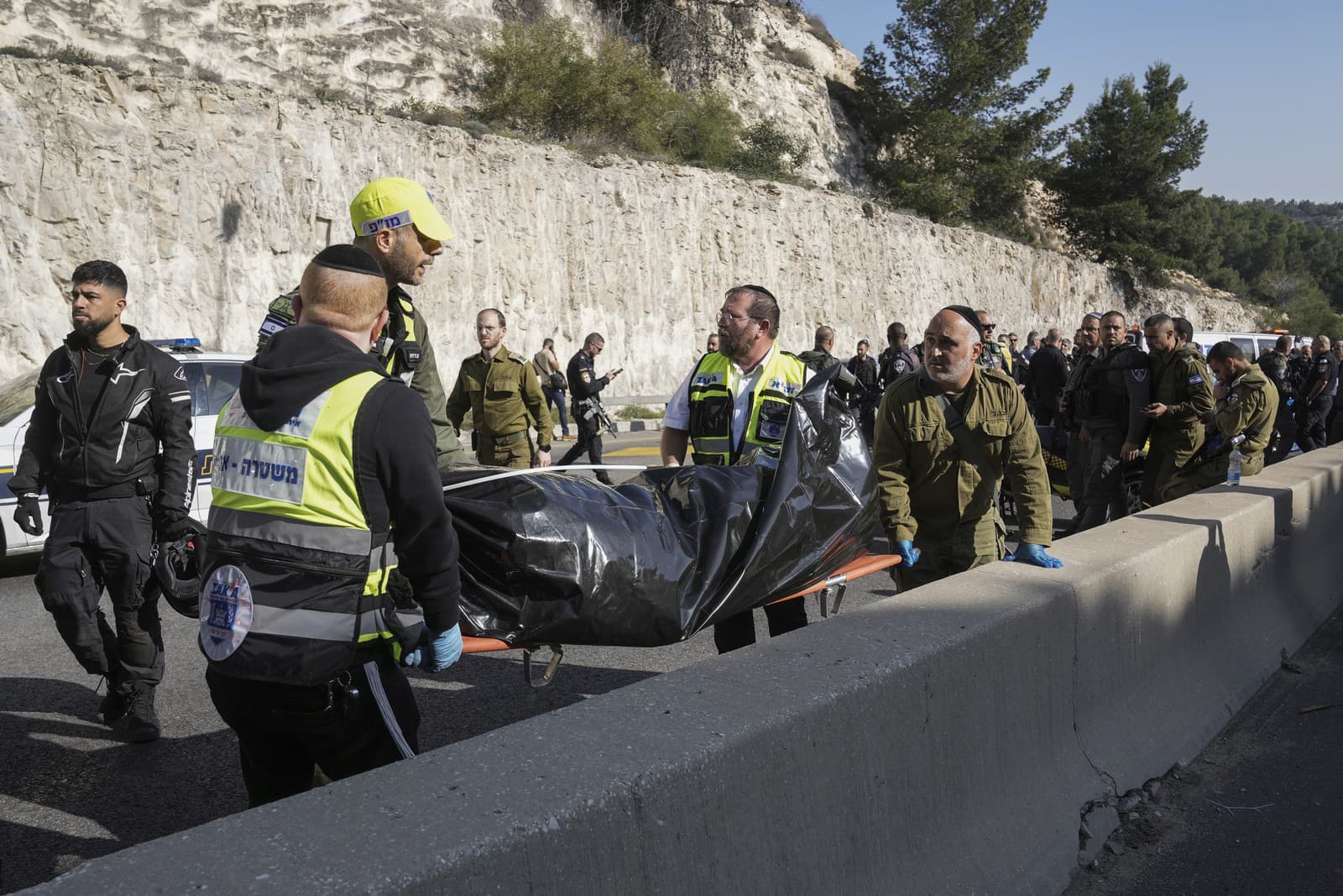 Príslušníci izraelských bezpečnostných síl a záchranári Zaka vynášajú telo z miesta streľby po útoku v izraelskej osade Maale Adumim