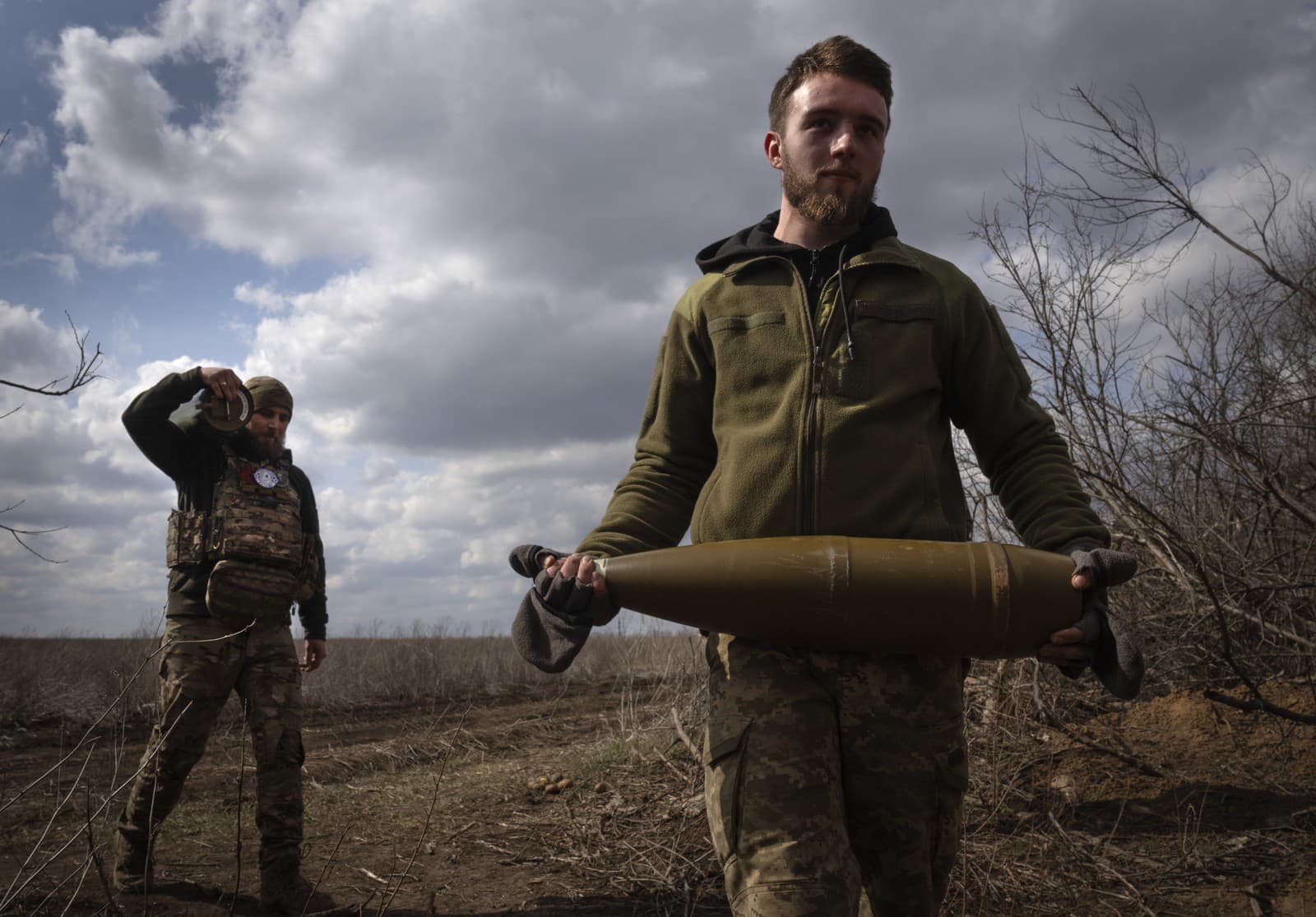 Ukrajinský vojak nesie na fronte delostreleckú muníciu 