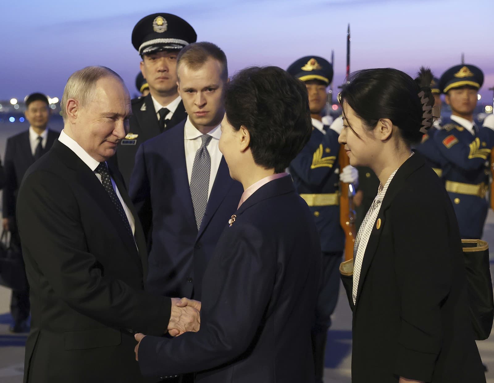 Ruský prezident Vladimir Putin (vľavo) si podáva ruku s čínskym štátnym radcom Šen I-čchinom (druhý sprava) po prílete na medzinárodné letisko v Pekingu vo štvrtok 16. mája 2024. 