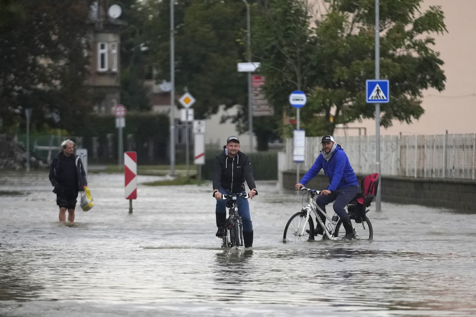 Obyvatelia jazdia na bicykloch po zaplavenej ulici v českom meste Litovel.