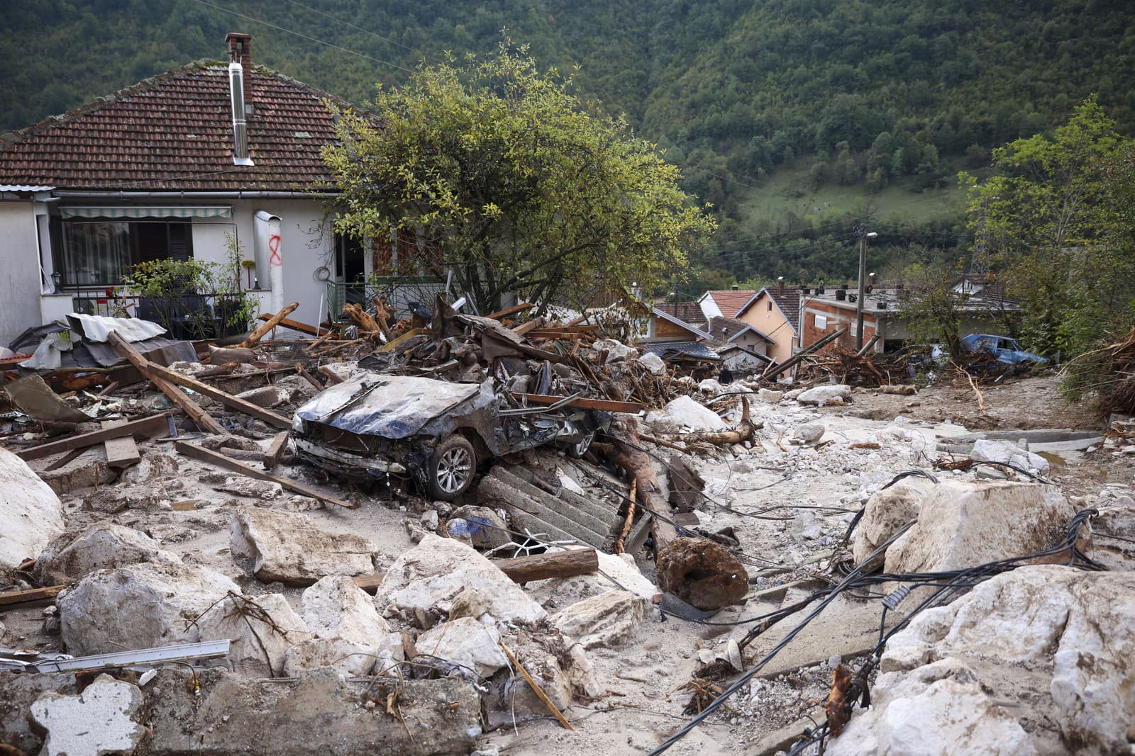 Zničené auto pri dome po záplavách a zosuvoch pôdy v bosnianskej dedine Donja Jablanica.