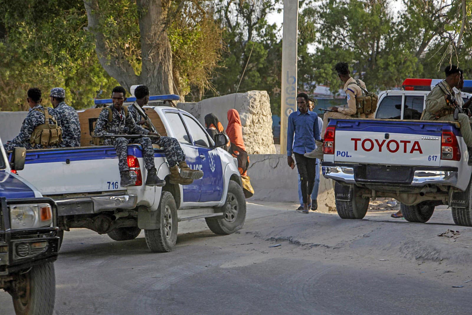 Deti kráčajú domov, vľavo somálska polícia hliadkuje neďaleko miesta útoku samovražedného atentátnika v kaviarni v somálskom Mogadiše vo štvrtok 17. októbra 2024.