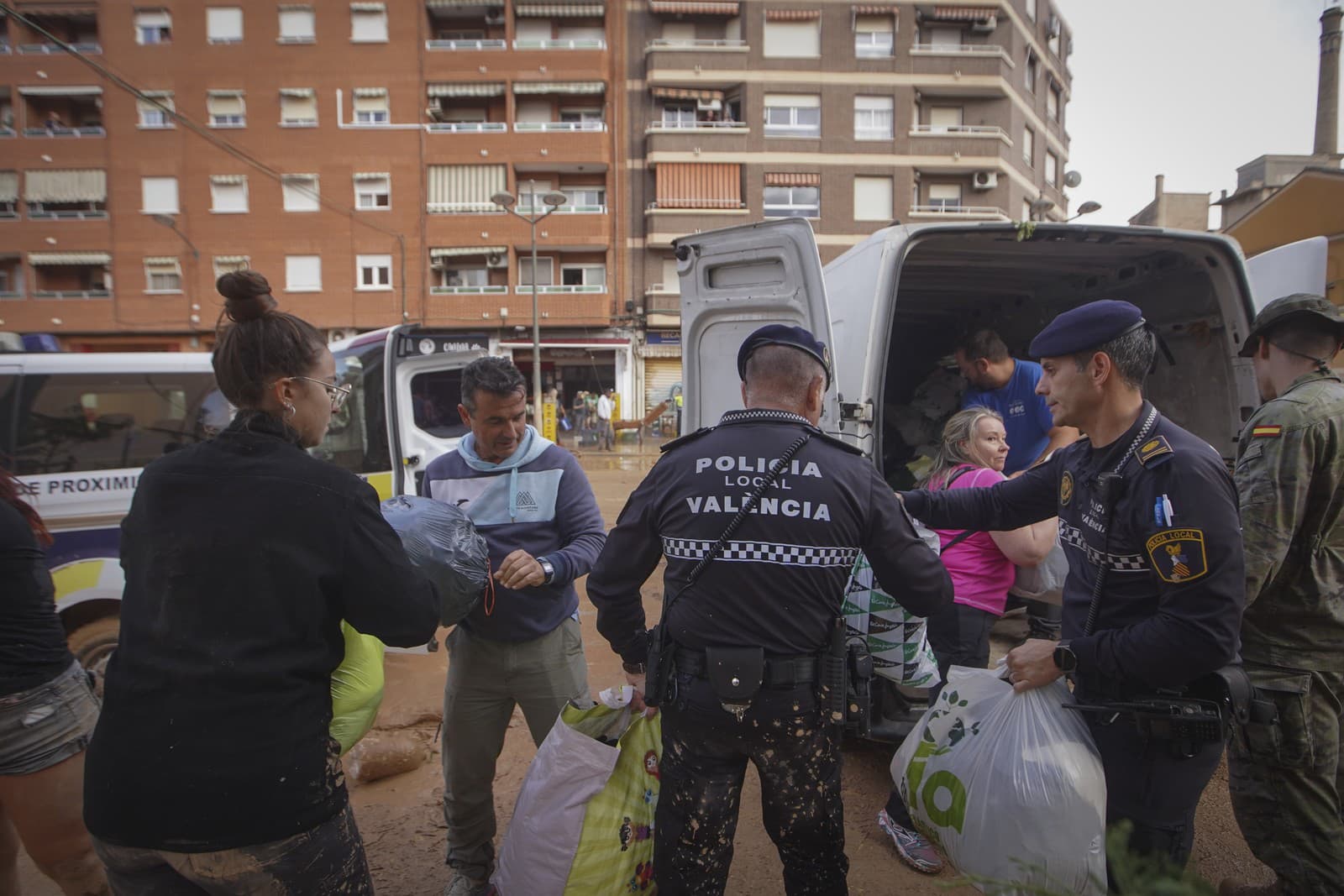 Obyvatelia, dobrovoľníci a polícia sťahujú pomoc pre obete záplav na asistenčnom mieste v Parrish v štvrti La Torre v španielskej Valencii.