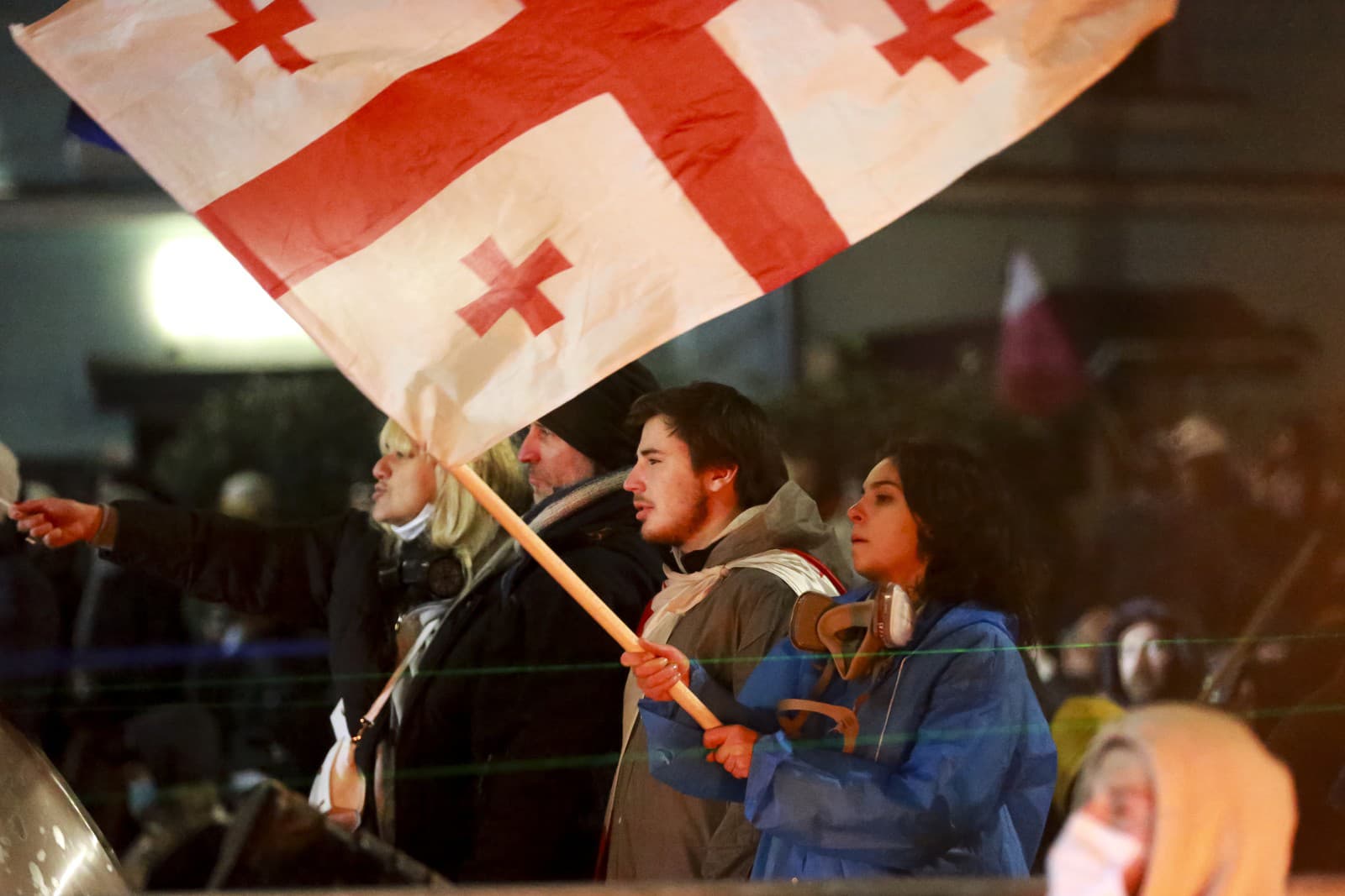 Jeden z demonštrantov drží gruzínsku národnú vlajku pred políciou, ktorá zablokovala ulicu, aby zabránila demonštrantom zhromaždiť sa proti rozhodnutiu vlády pozastaviť rokovania o vstupe do Európskej únie na štyri roky pred budovou parlamentu v gruzínskom Tbilisi.