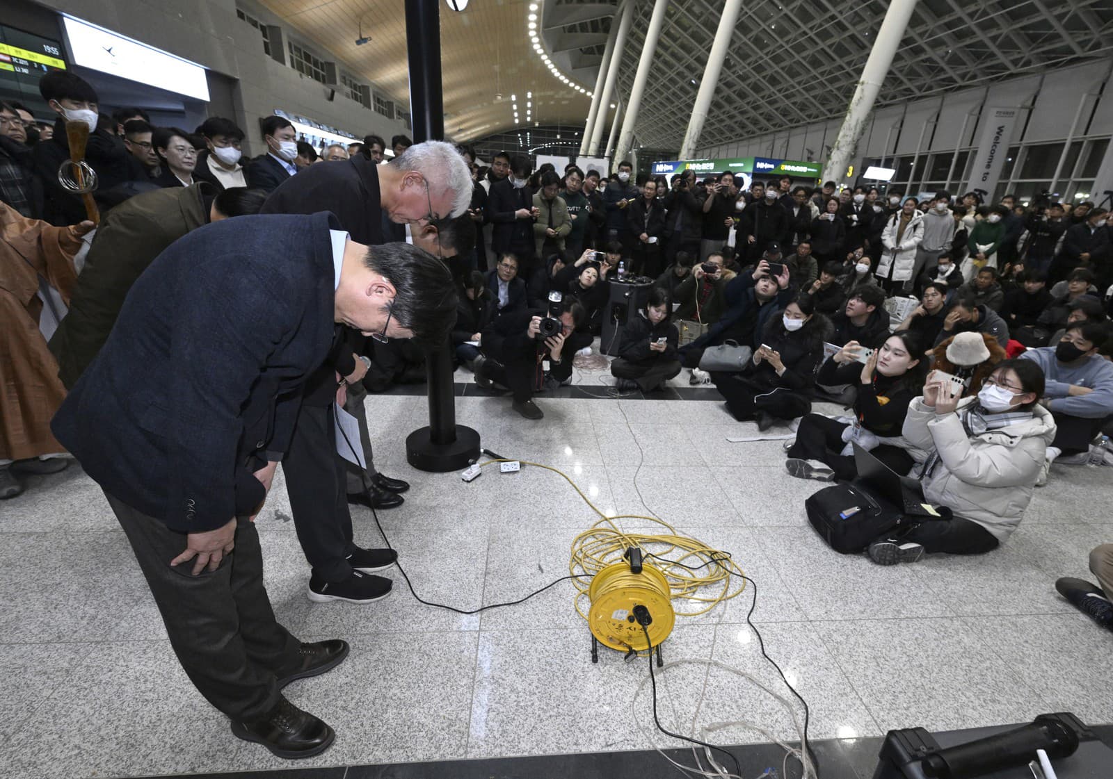 Šéf nízkonákladovej leteckej spoločnosti Jeju Air Kim Yi-bae (vľavo) a ďalší členovia vedenia sa ospravedlňujú príbuzným cestujúcich na medzinárodnom letisku Muan v Južnej Kórei.