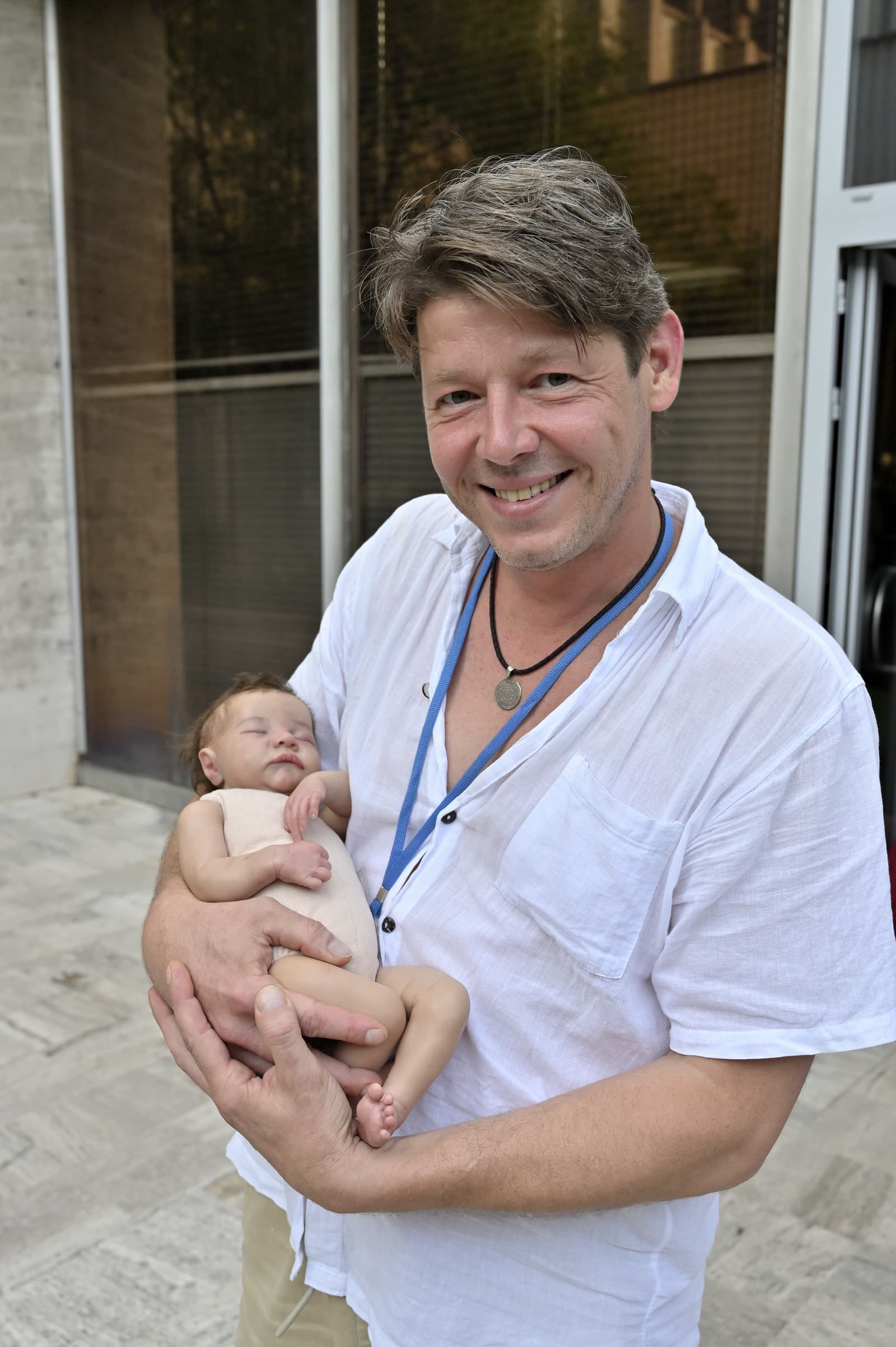 Ondřej Daniš v seriáli Dotyk života, v náručí drží silikónovú bábiku