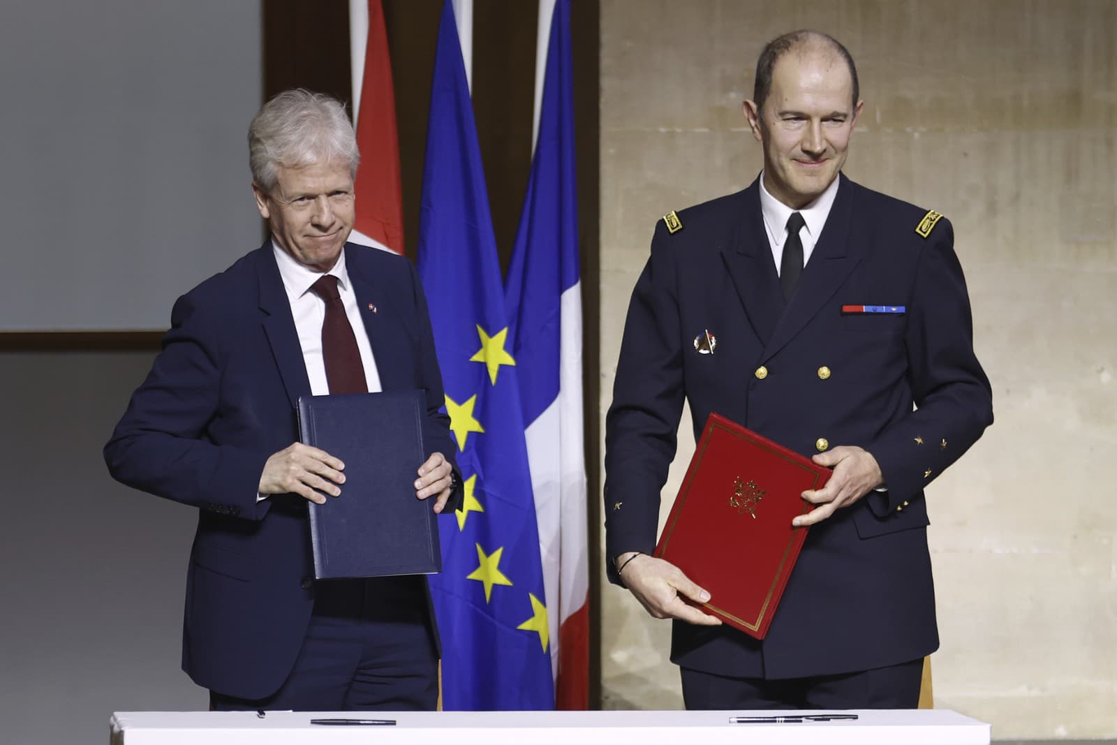 Vedúci oddelenia vývoja/zástupca riaditeľa národného materiálu dánskeho ministerstva obrany Peter Michael Nielsen a vedúci oddelenia dopravných lietadiel, rakiet a vrtuľníkov AT DGA generálmajor Emmanuel Laporte podpisujú kúpnu zmluvu o obrane