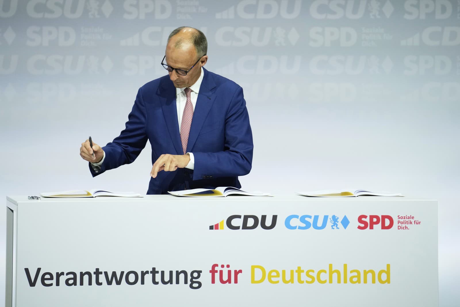 Predseda CDU Friedrich Merz podpisuje koaličnú zmluvu.