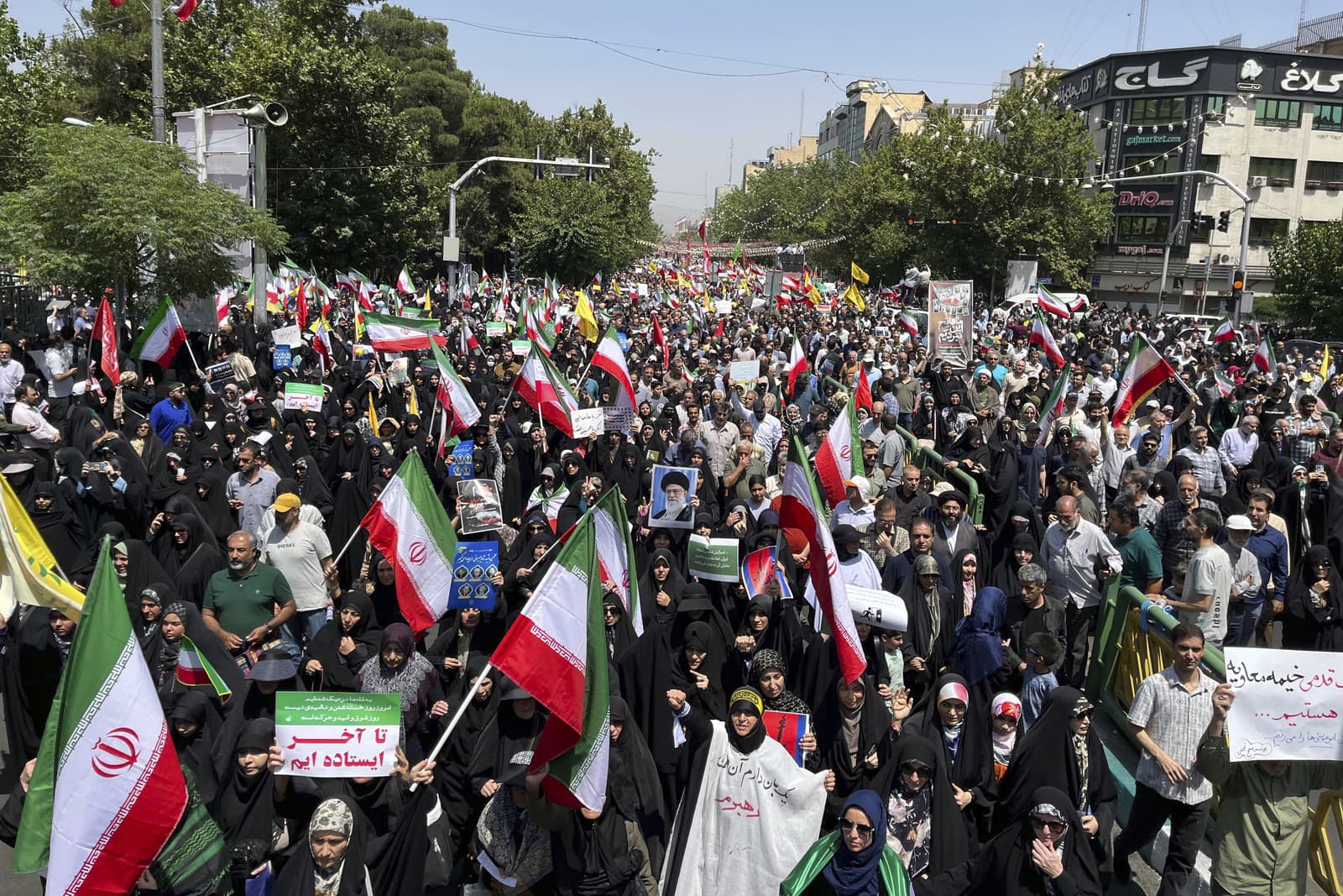 Iránski veriaci mávajú iránskymi vlajkami a jeden z nich drží plagát iránskeho najvyššieho vodcu ajatolláha Alího Chameneího počas protestu proti izraelským útokom na viaceré mestá v Iráne po piatkových modlitbách v centre Teheránu.