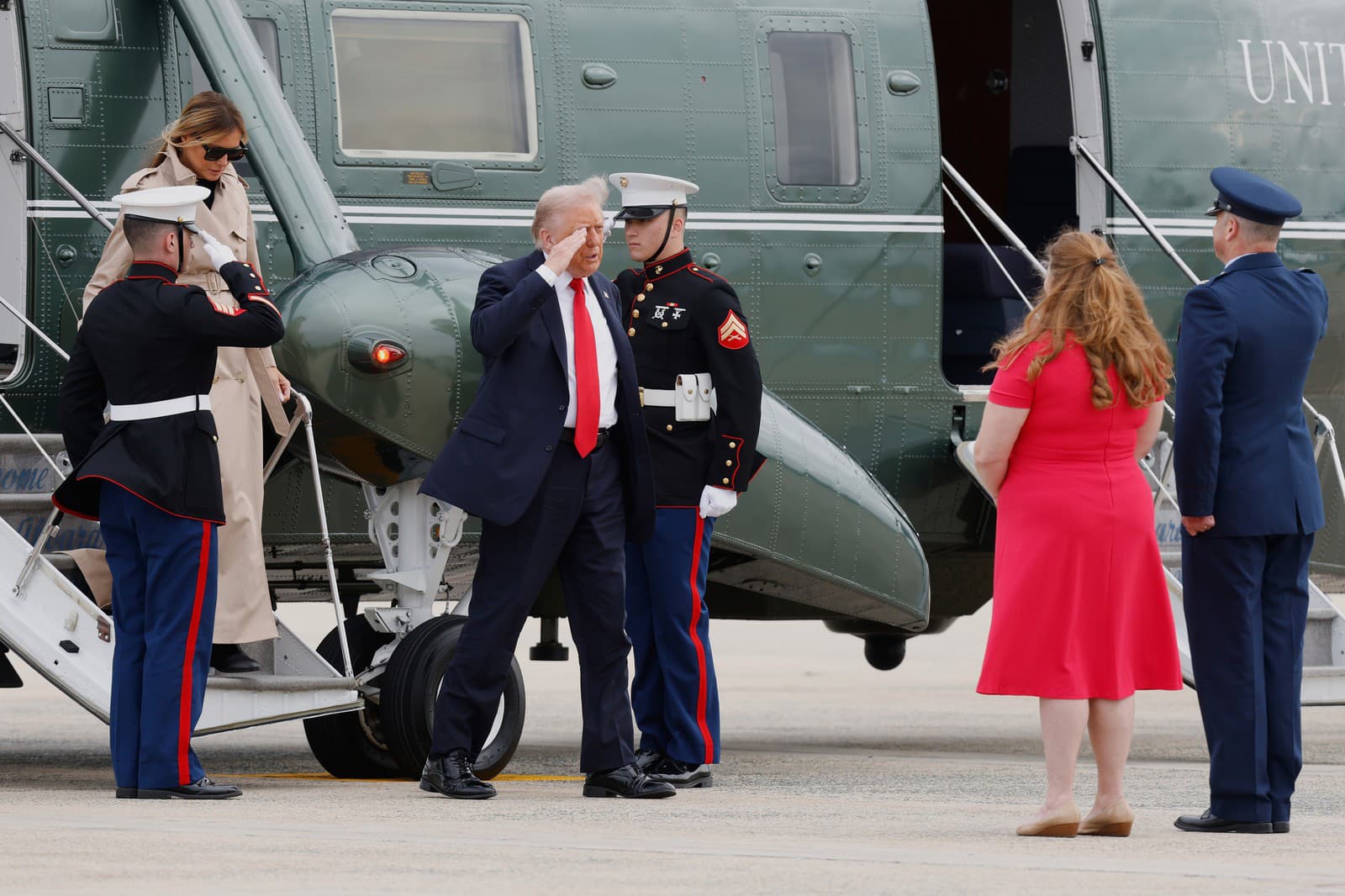 Prezidenta Donalda Trumpa (v strede) a jeho manželku Melaniu Trumpovú (vľavo hore) víta plukovník letectva Christopher M. Robinson, veliteľ 89. prepravného krídla (vpravo), a jeho manželka Stephanie Robinsonová (druhá sprava) pred nástupom do lietadla