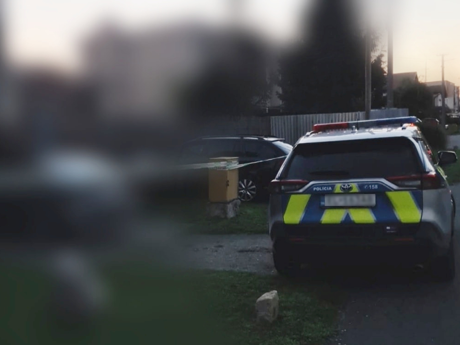 Fotografia policajného auta spred domu, kde došlo k vražde