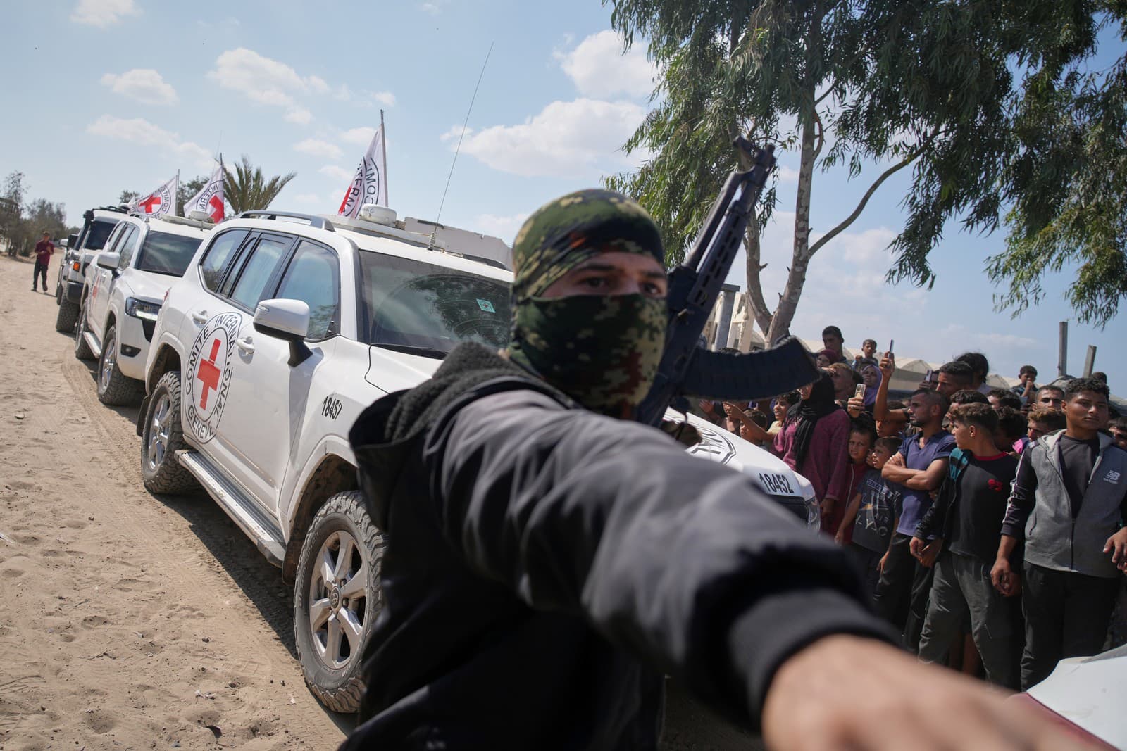 Vozidlá MVČK s prepustenými izraelskými rukojemníkmi si razia cestu cez skupiny Palestínčanov a ozbrojencov Hamasu na ceste k izraelským hraniciam v Chán Júnis na juhu pásma Gazy.