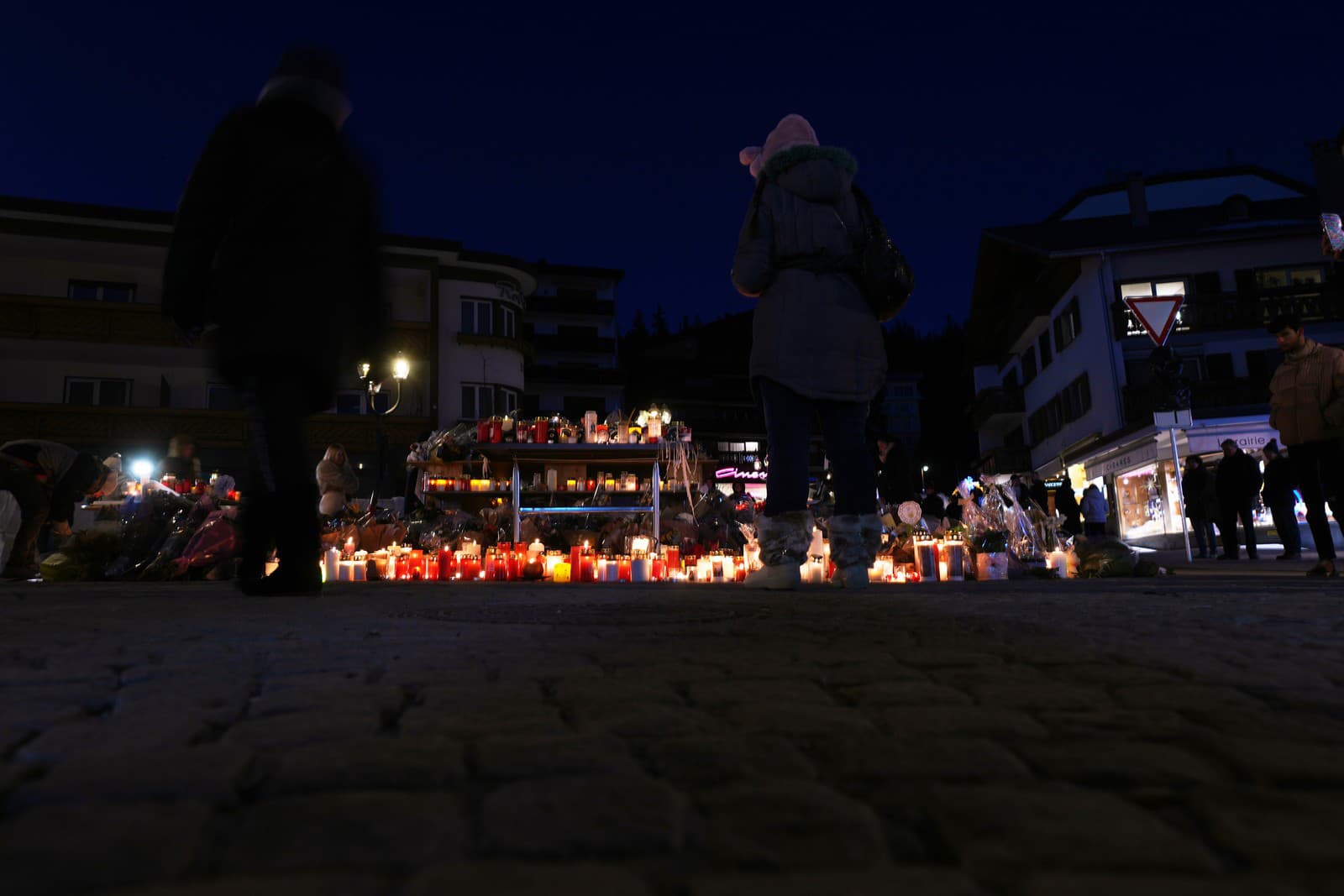 Ľudia zapaľujú sviečky a kladú kvety na pamiatku obetí neďaleko vyhoreného baru Le Constellation v Crans-Montane