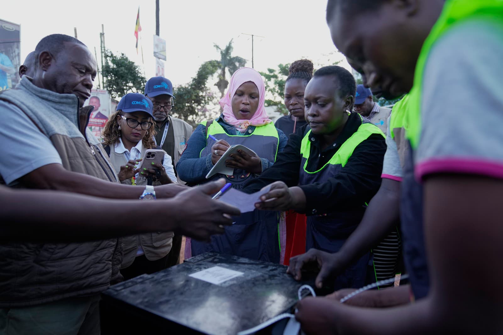 Ugandskí voliči pozorujú otvorené hlasovacie lístky počas hlasovania v prezidentských a parlamentných voľbách v Ugande vo volebnej miestnosti v Kampale.