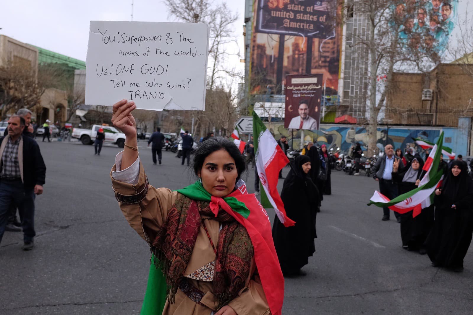 Žena bez povinnej pokrývky hlavy drží transparent na provládnej demonštrácii v Teheráne proti útokom USA a Izraela.