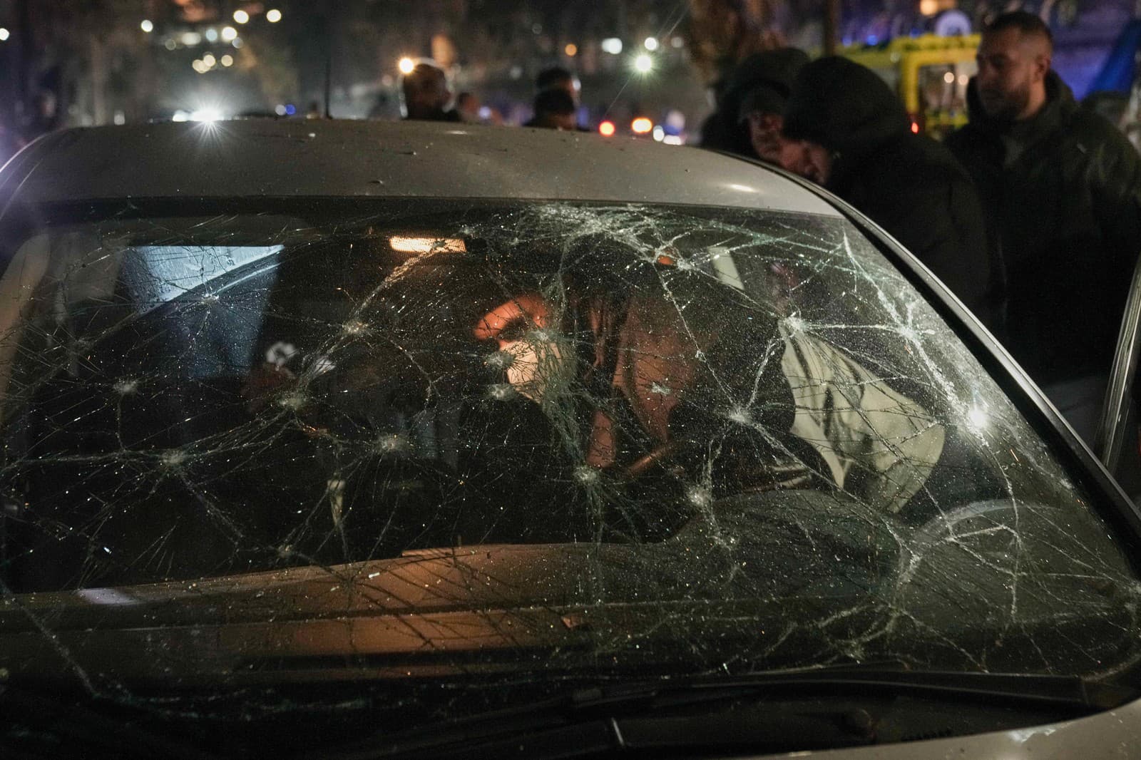 Muž si prezerá poškodené auto po izraelskom leteckom útoku na verejnej pláži v Bejrúte v Libanone