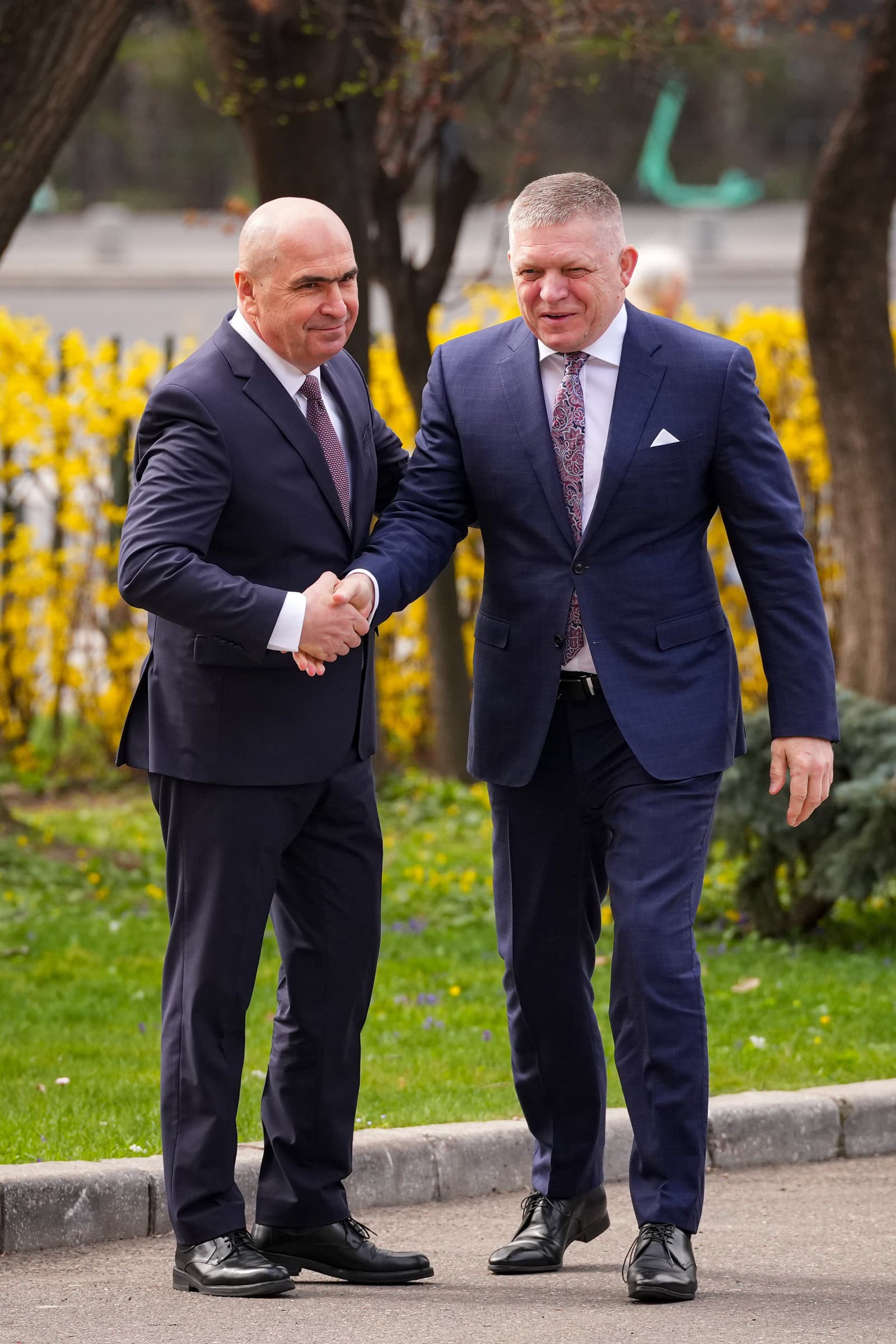 Slovenský premiér Robert Fico (vľavo) a jeho rumunský náprotivok Ilie Bolojan kráčajú počas uvítacieho ceremoniálu v Bukurešti v piatok 27. marca 2026.