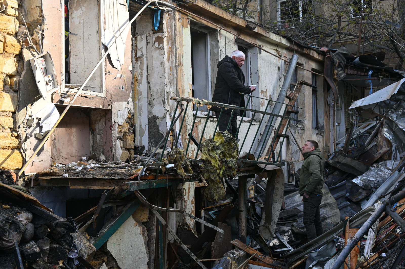 Zranený muž stojí na dvore obytného domu zničeného ruským útokom na Odesu.