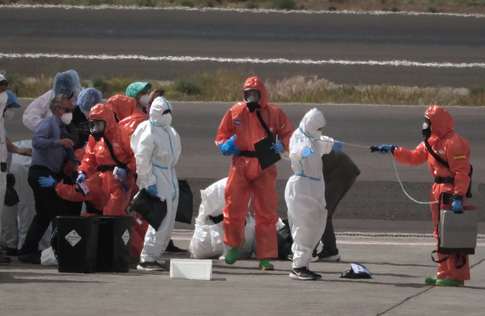 Pasažieri lode, ktorých dezinfikujú zástupcovia španielskych úradov pred nástupom do lietadla na letisku na Tenerife