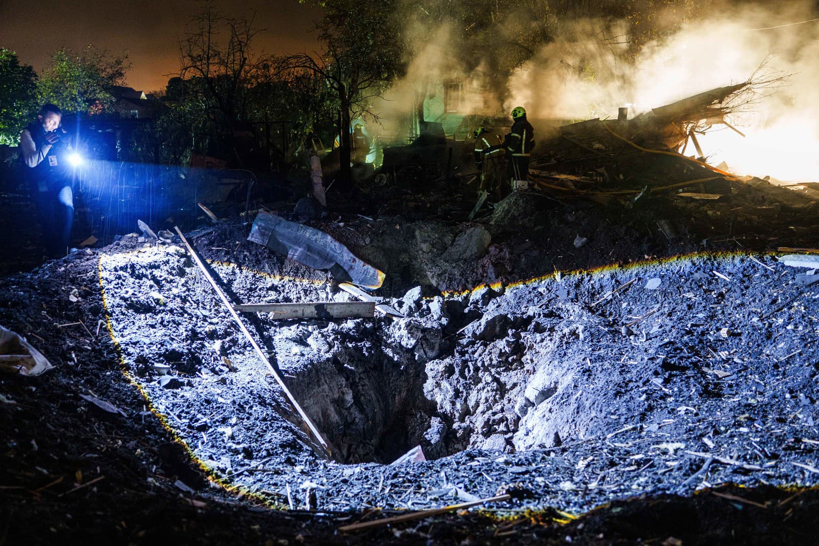 Ľudia sa po ruskom raketovom útoku pozerajú na škody v obytnej štvrti v Kyjeve.