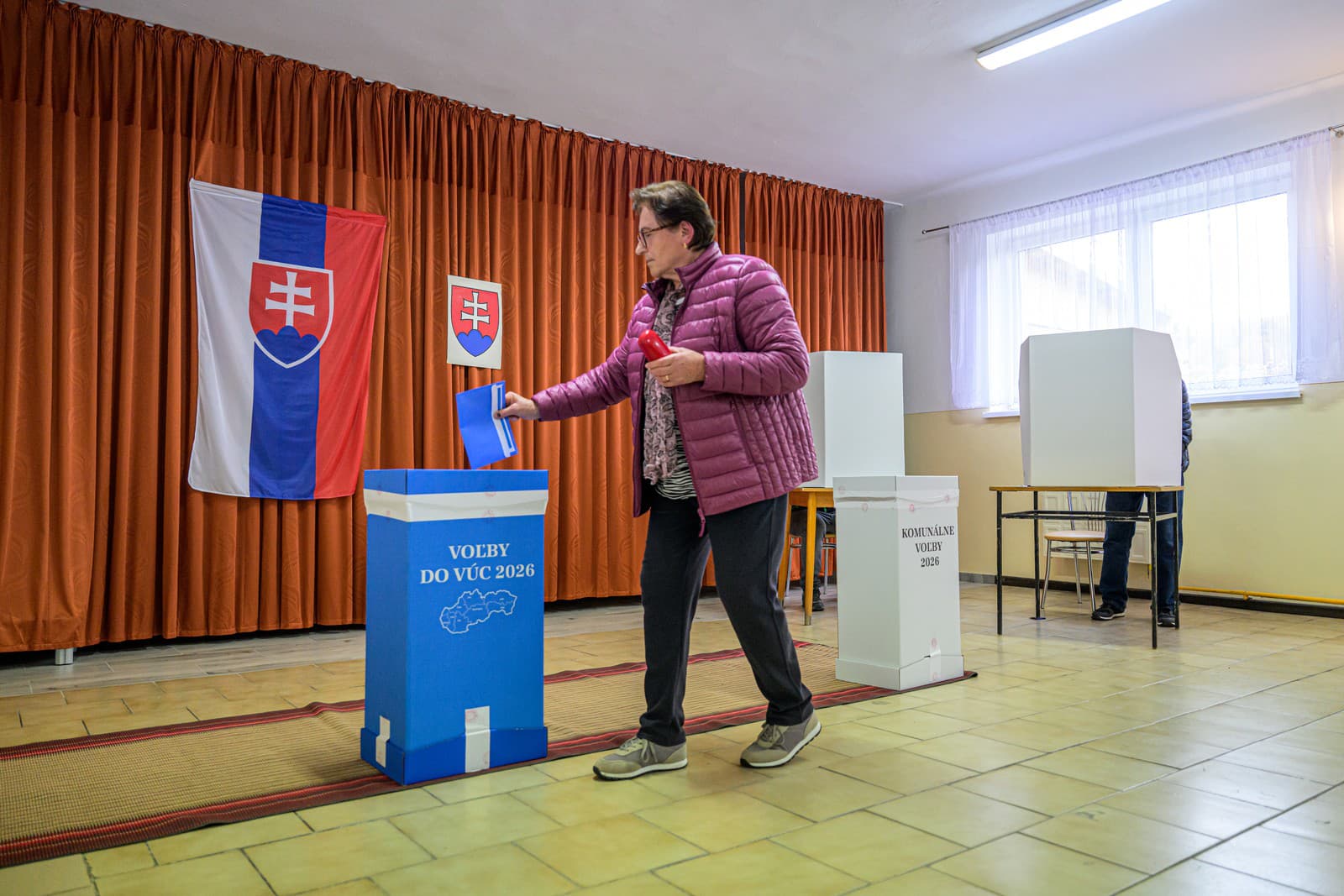 Volička vhadzuje obálku s hlasovacími lístkami do volebnej schránky pre voľby do VÚC vo volebnej miestnosti v obci Rokytov 