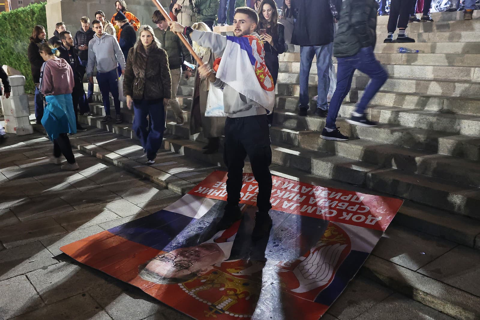 Muž oslavuje, stojac na znehodnotenom plagáte Aleksandara Vučića, lídra pravicovej Srbskej pokrokovej strany (SNS), po tom, čo tento priznal porážku v parlamentných voľbách v Belehrade.
