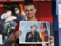Migrant nesie pri príchode do Mníchova v ruke portrét Angely Merkelovej.